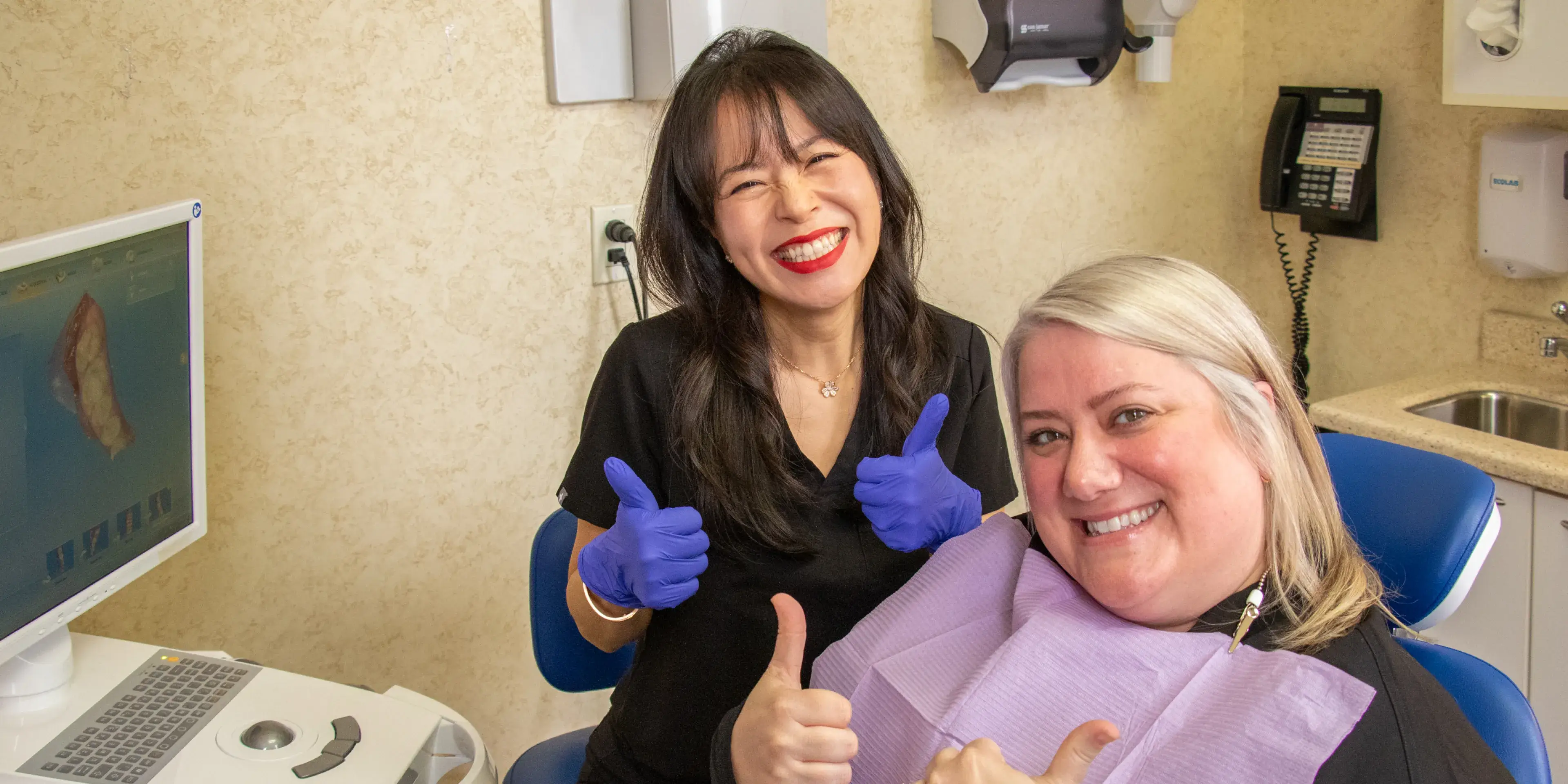 Young woman with glasses, wearing a blue sweater, looking thoughtful with hand on chin.