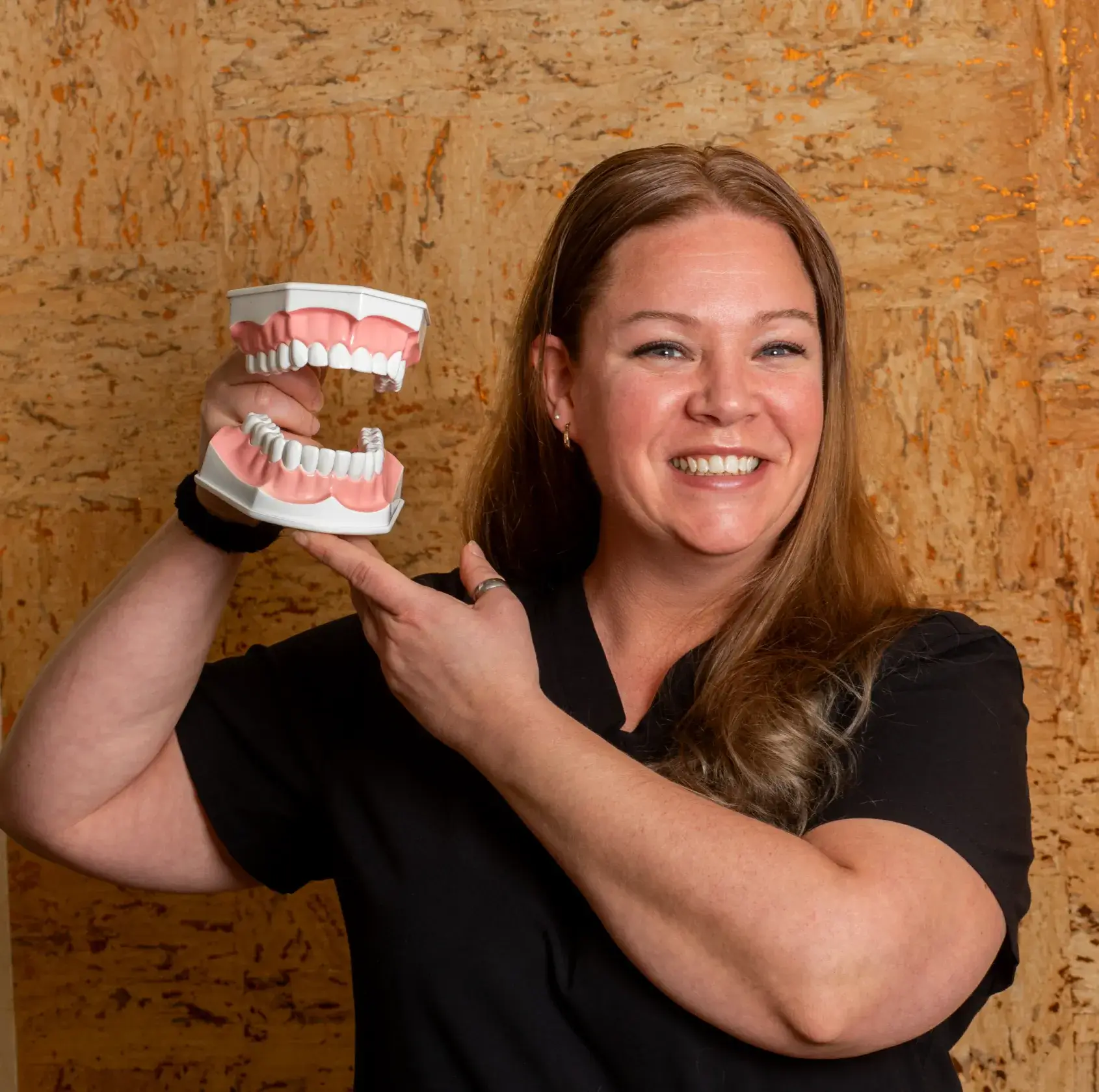 A dentist talks and smiles with a patient sitting in a dental chair.