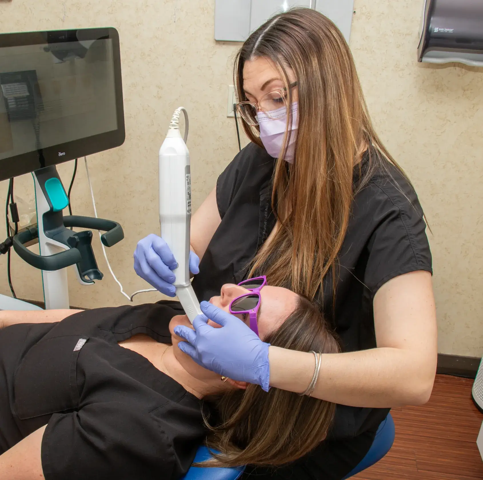 A woman smiling holds a small, smiling tooth-shaped toy in her hand.