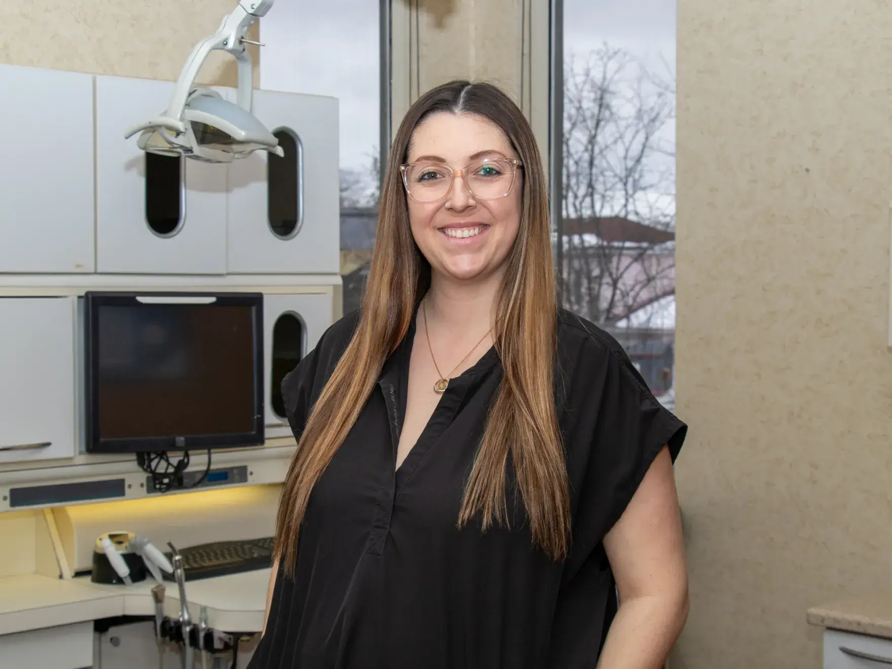 A woman with light hair smiling and holding a tablet in her hands.