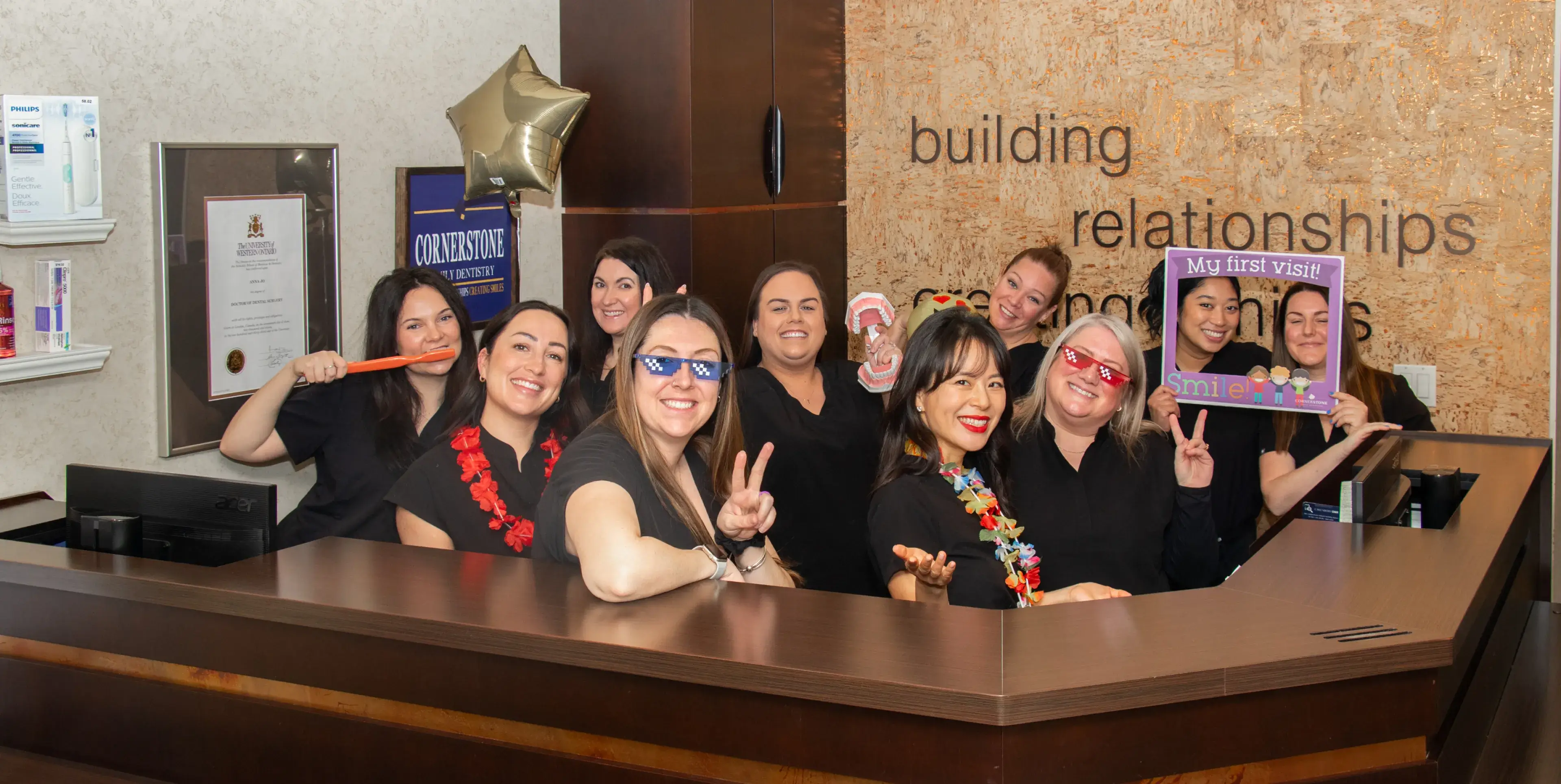 A group of women wearing black uniforms stand together and smile inside an office reception area.