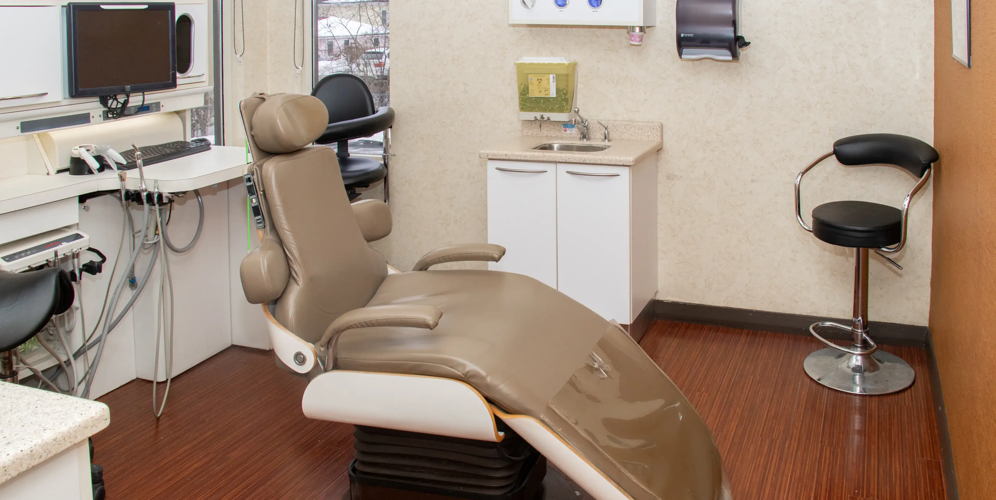 Empty dentist's office with a reclining chair and dental equipment on the countertop.