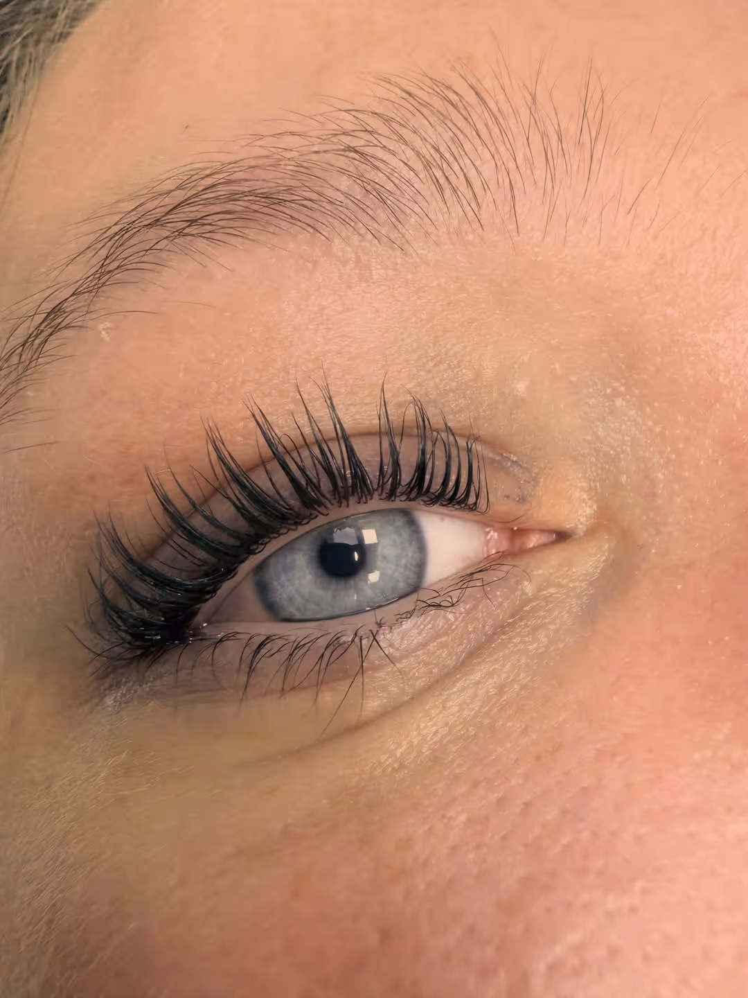 Nahaufnahme eines Auges mit gehobenen und verlängerten Wimpern.