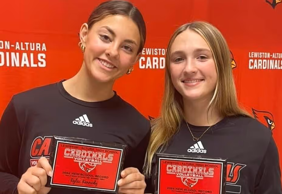 Female athletes holding college commitment certificates