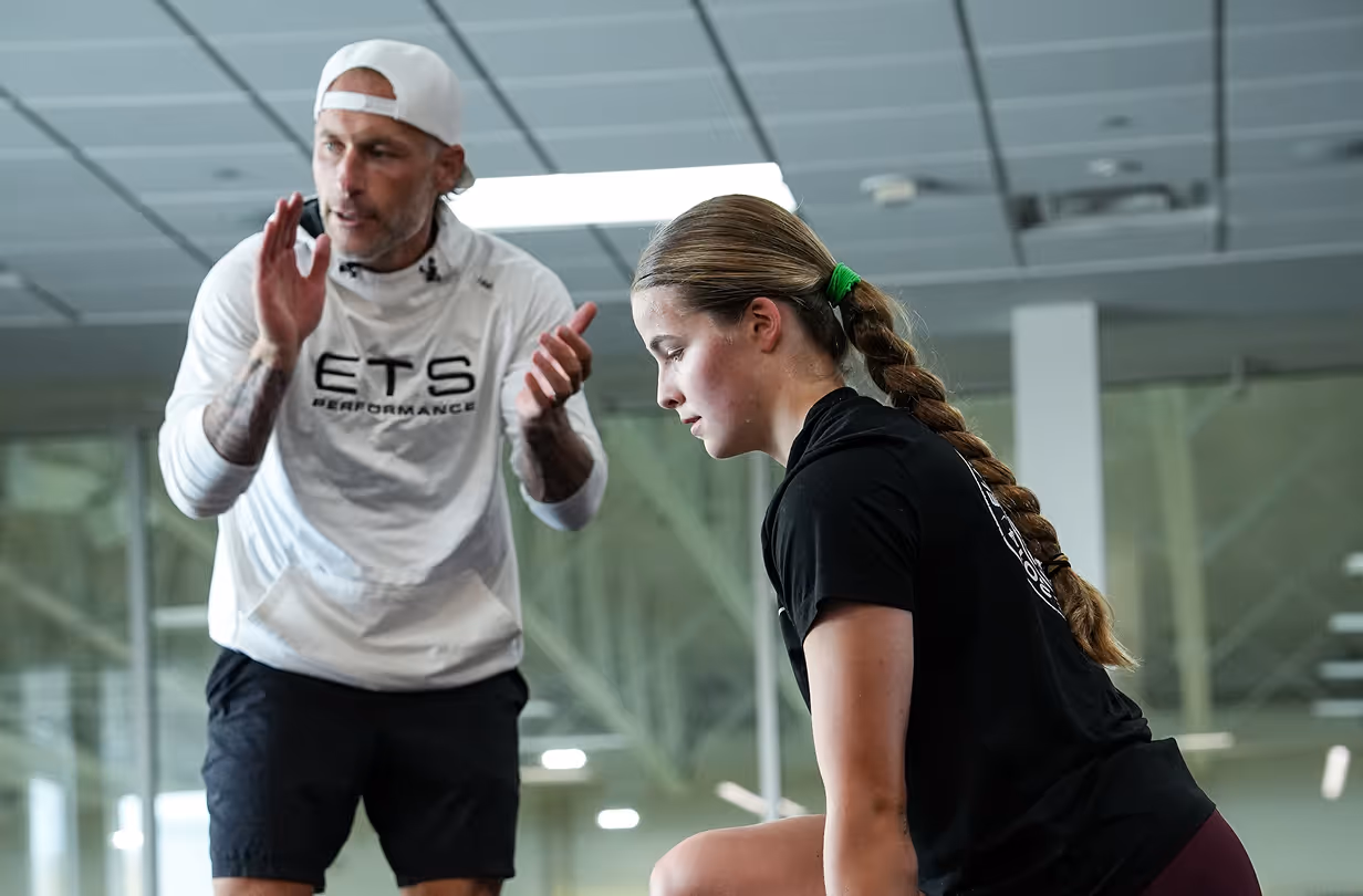 Athlete performing strength training exercise with coach supervision