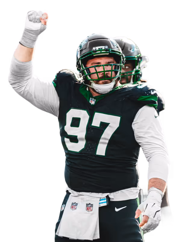American football defensive player in green and white uniform raising one arm