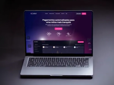 Laptop displaying a website with a dark purple theme and Portuguese text about automated payments.