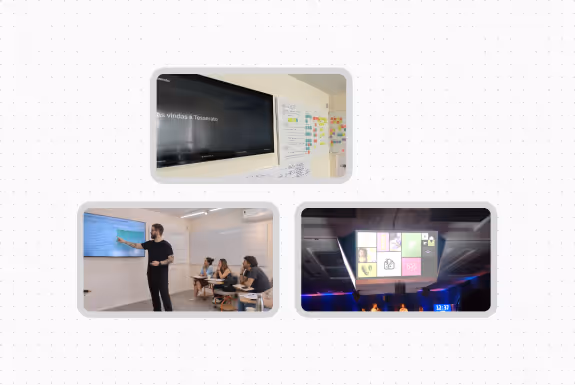 Group of people sitting in a classroom watching a screen displaying a presentation with a whiteboard in the background.