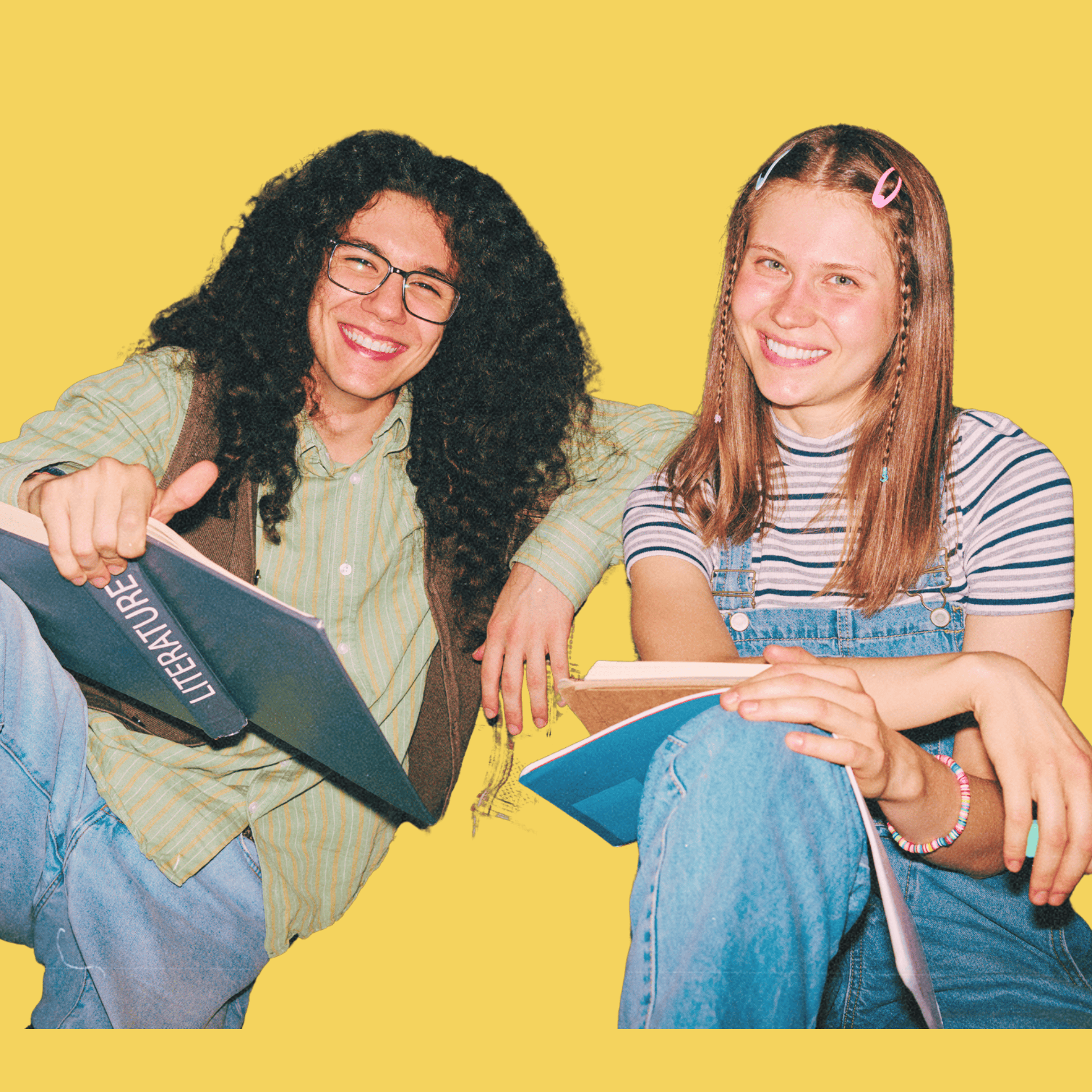 Smiling young man with curly hair holding a literature book and a young woman with braided hair and hair clips holding a notebook, both sitting against a yellow background.