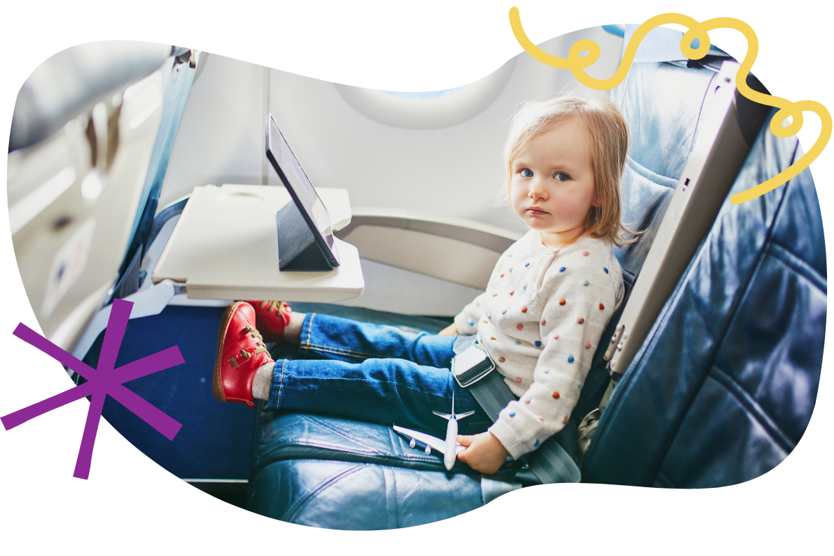 toddler sitting in an airplane seat with a tablet in front of her