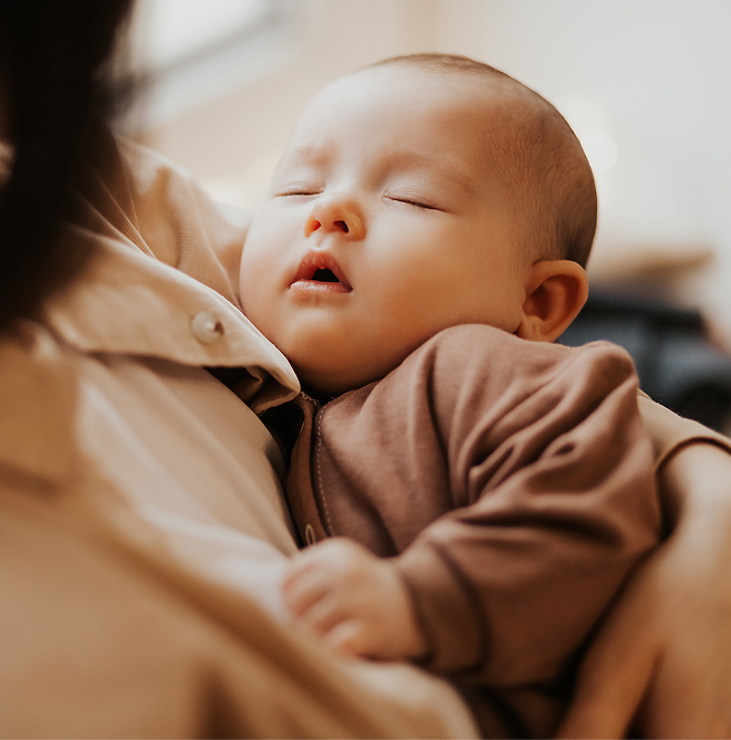 Infant sleeping in an adults arms