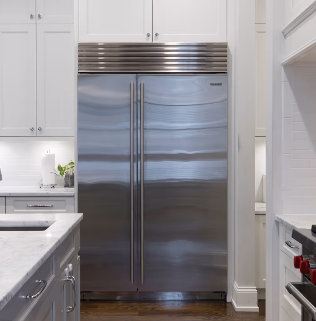 Built-in stainless steel refrigerator integrated into modern white kitchen cabinetry.