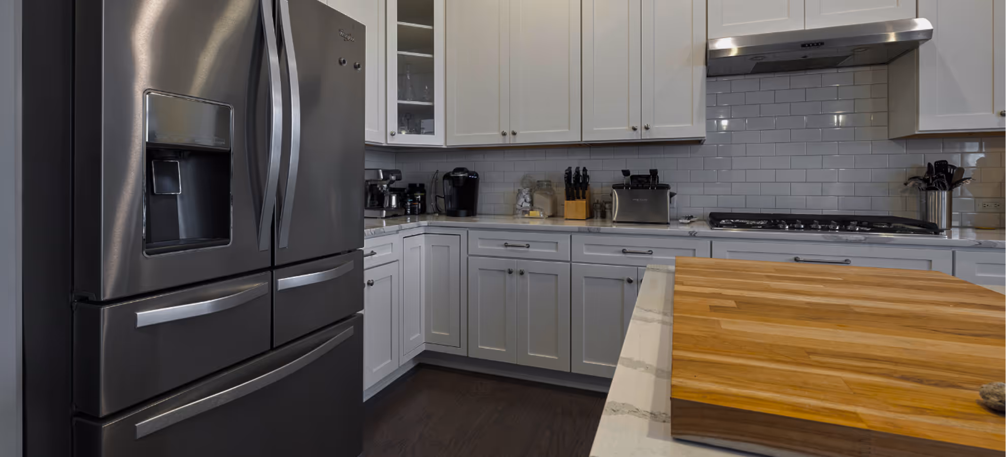 Stainless steel French door refrigerator in a modern kitchen with white cabinets