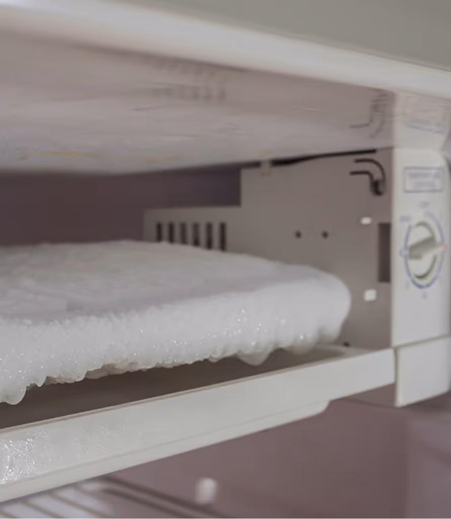 Freezer shelf covered with heavy ice buildup and frost.