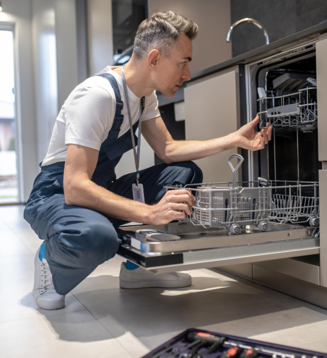 Technician inspecting open dishwasher during repair