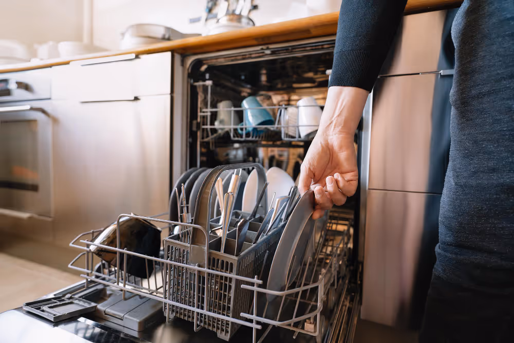 Person pulling out lower dishwasher rack with dishes