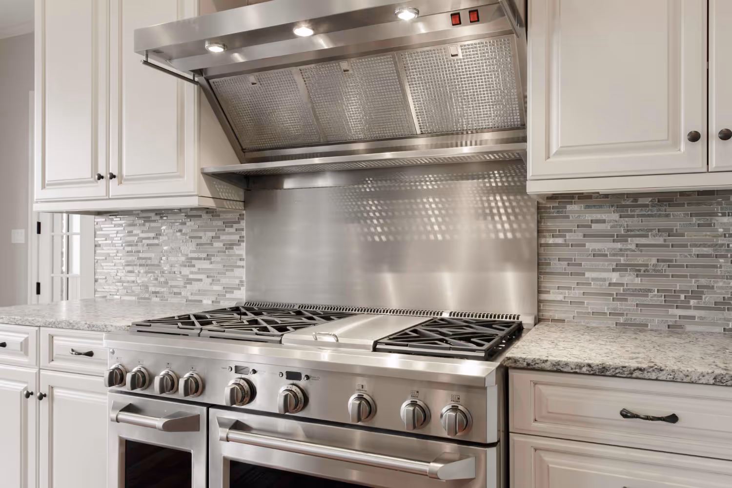 Large stainless steel double-oven gas range in a modern home kitchen