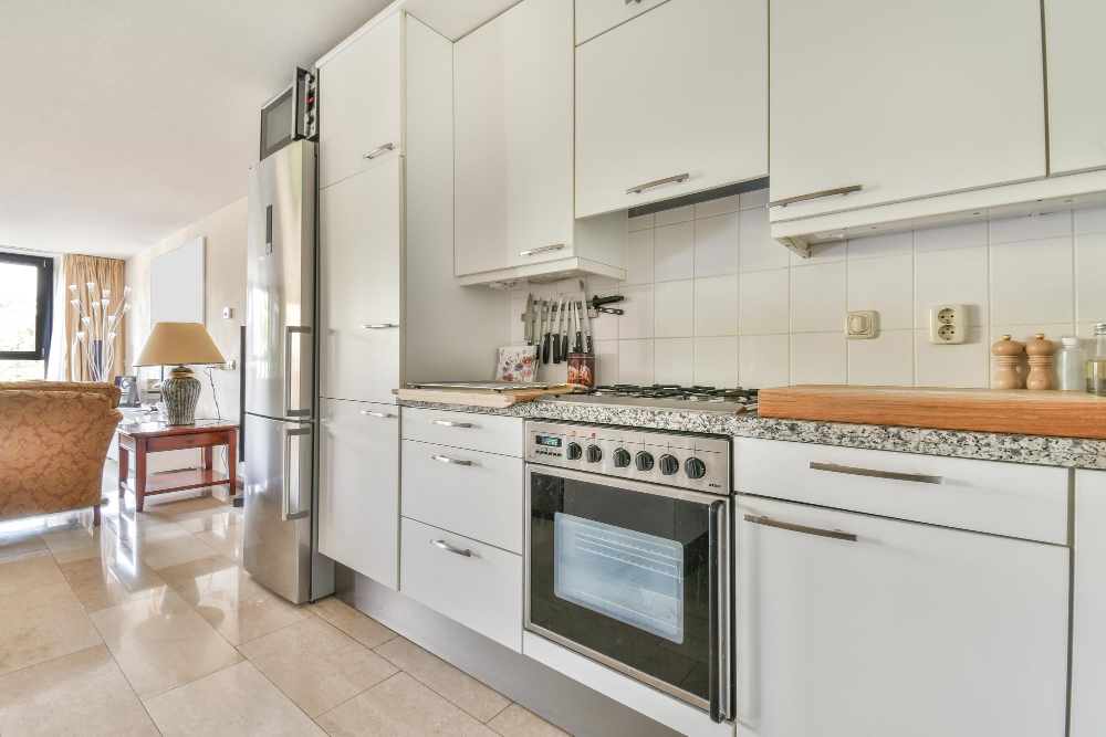 Modern white kitchen with built-in oven, gas cooktop, and stainless steel refrigerator