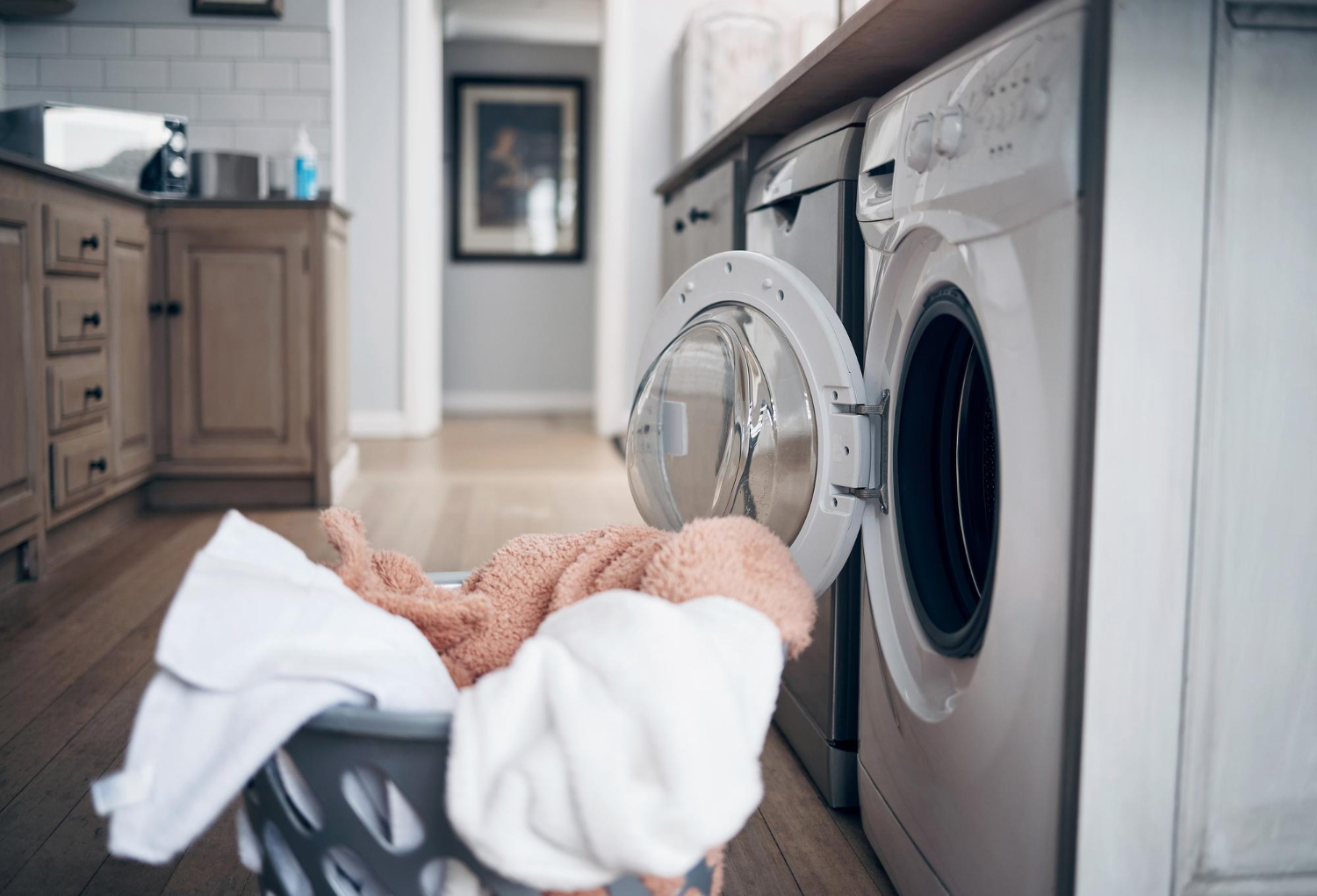 Front load washing machine with open door and laundry basket on floor showing washer not spinning issue