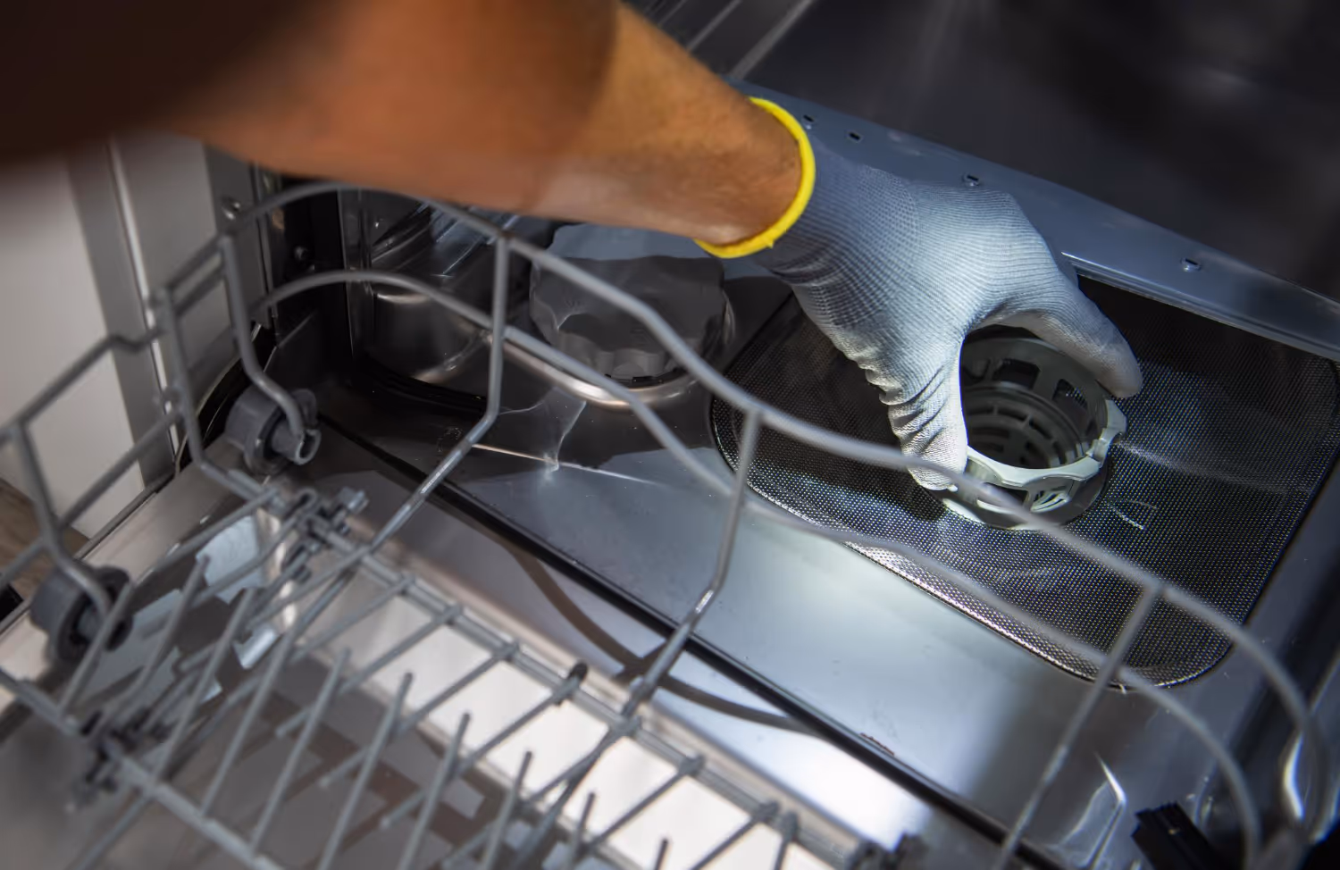Technician cleaning dishwasher filter during dishwasher repair