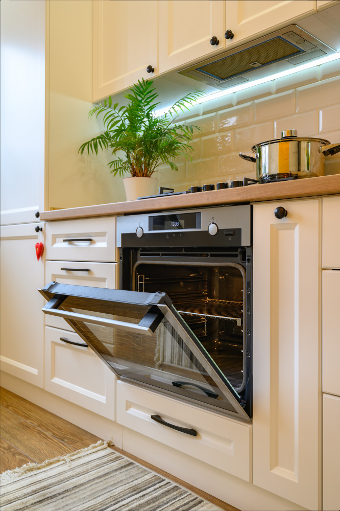 Open oven in bright kitchen with cooktop and cabinets in Jurupa Valley