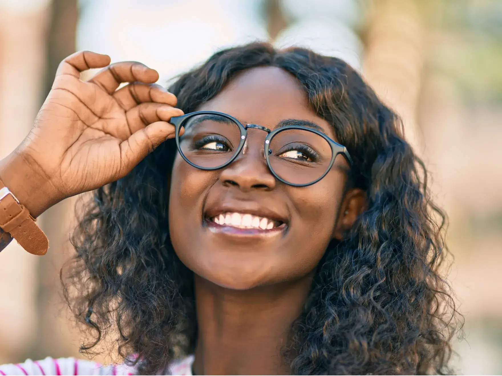 Young woman with glasses smilig at the camara in a natural enviroment