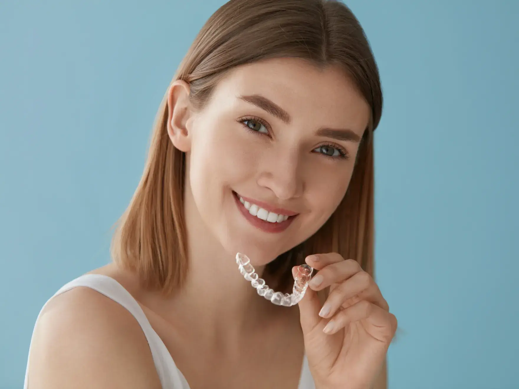 Woman smiling with aligners in a blue background 