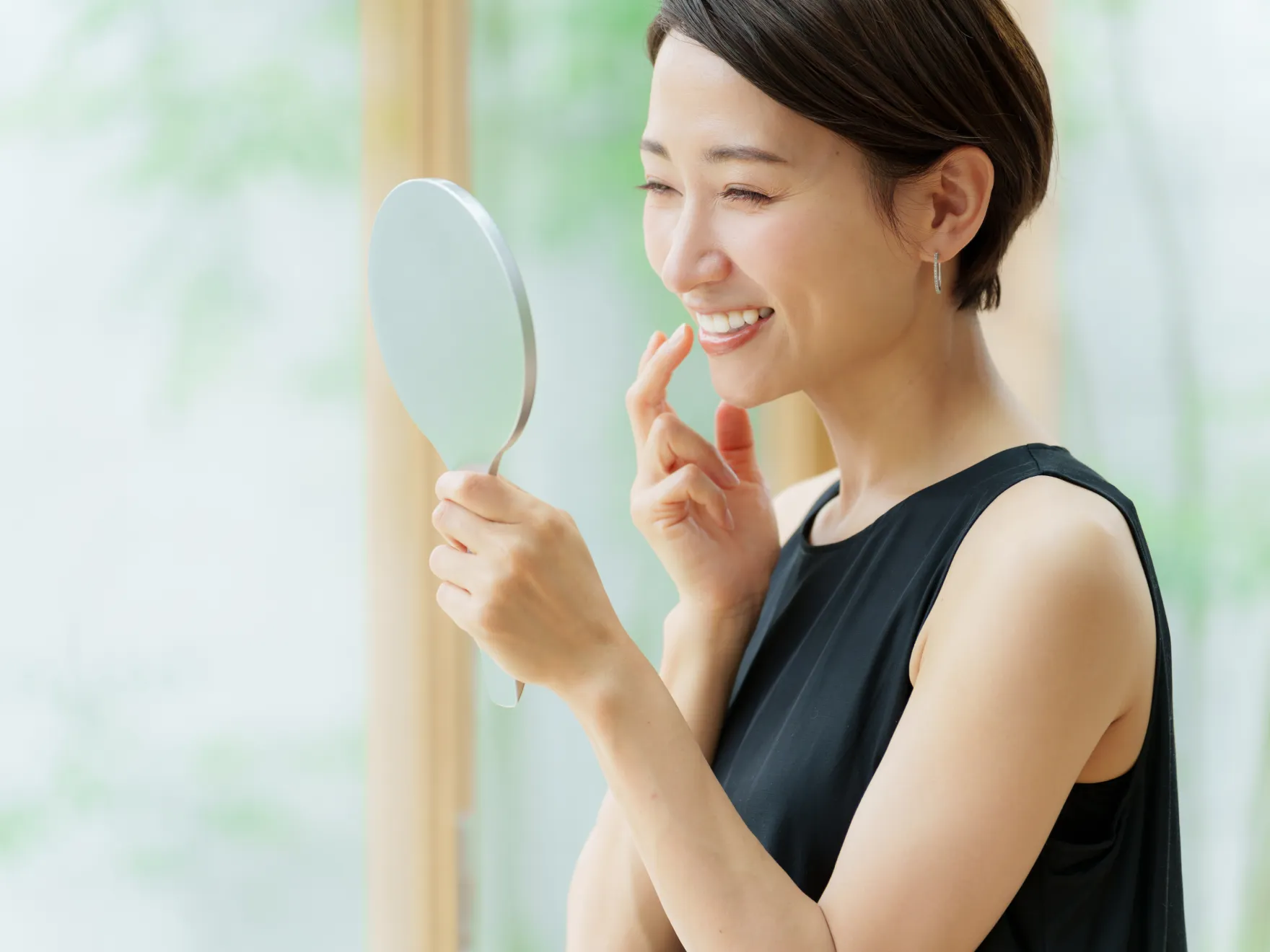 Woman looking happily at her teeth in the mirror.