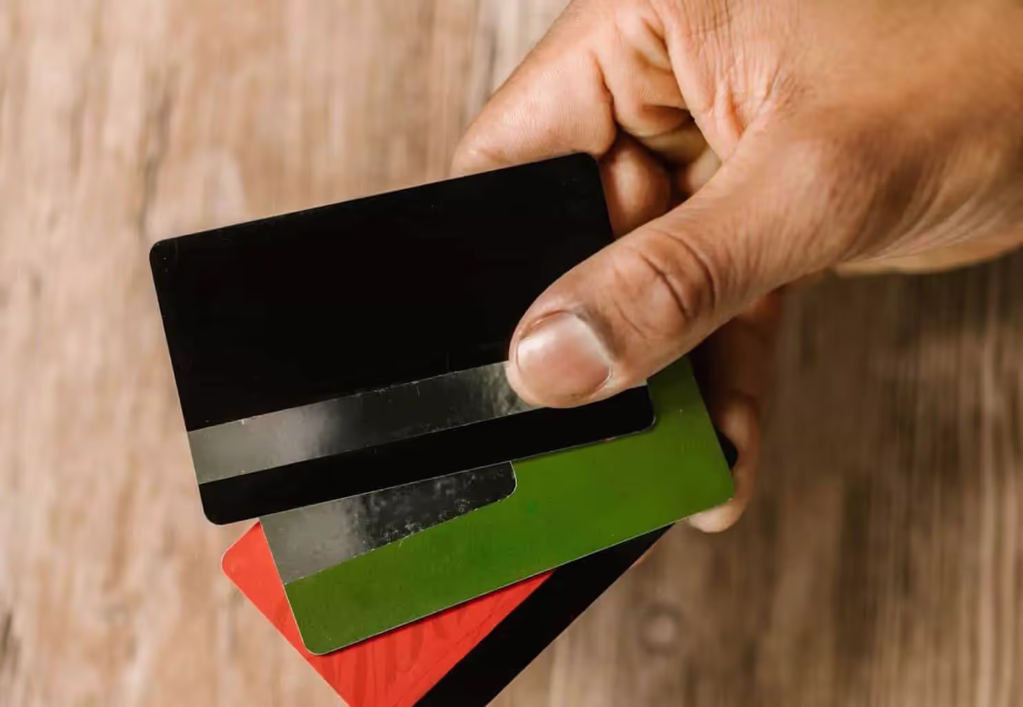 Hand holding black, green, and red credit cards
