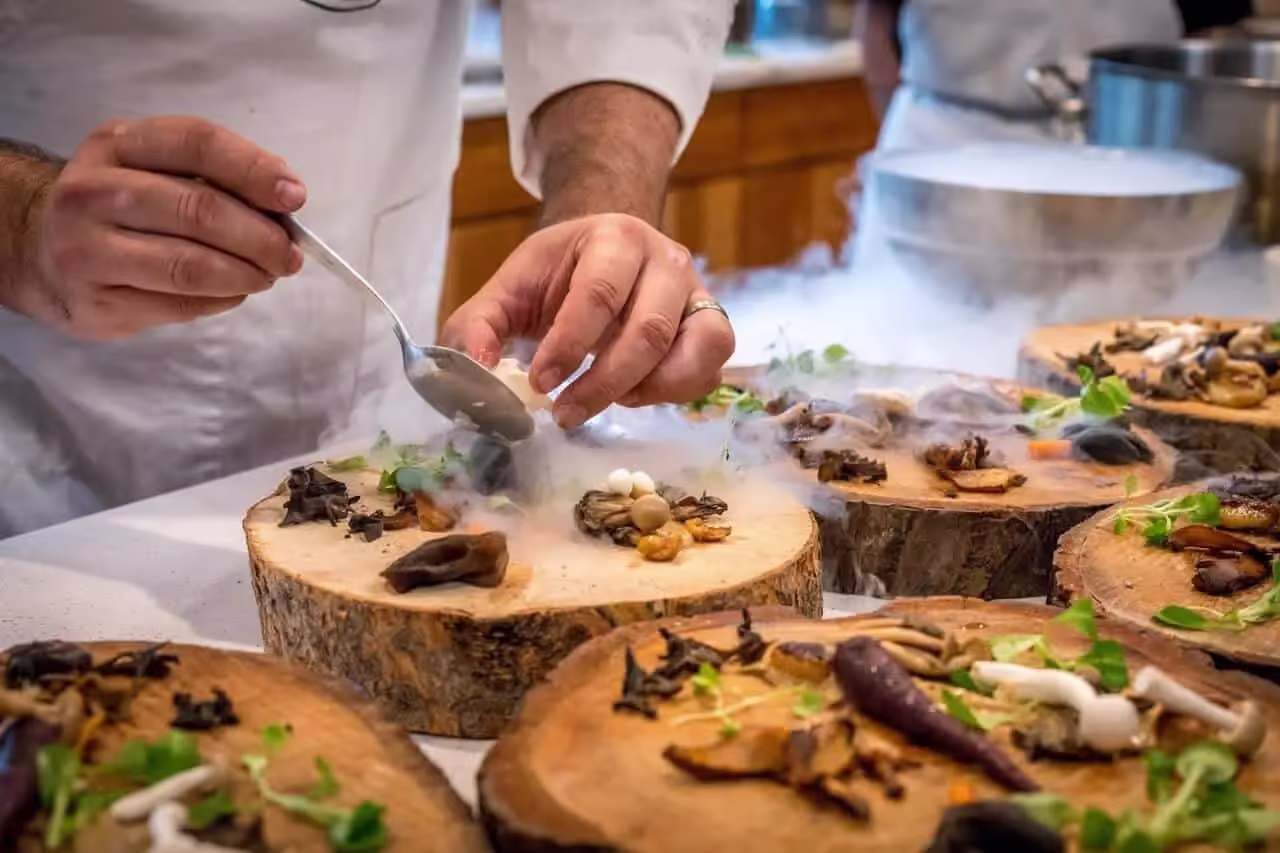 Chef placing food on a wooden serving plate made from a slice of a tree trunk