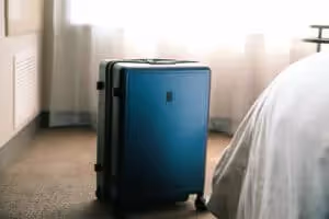Suitcase on hotel room floor next to bed