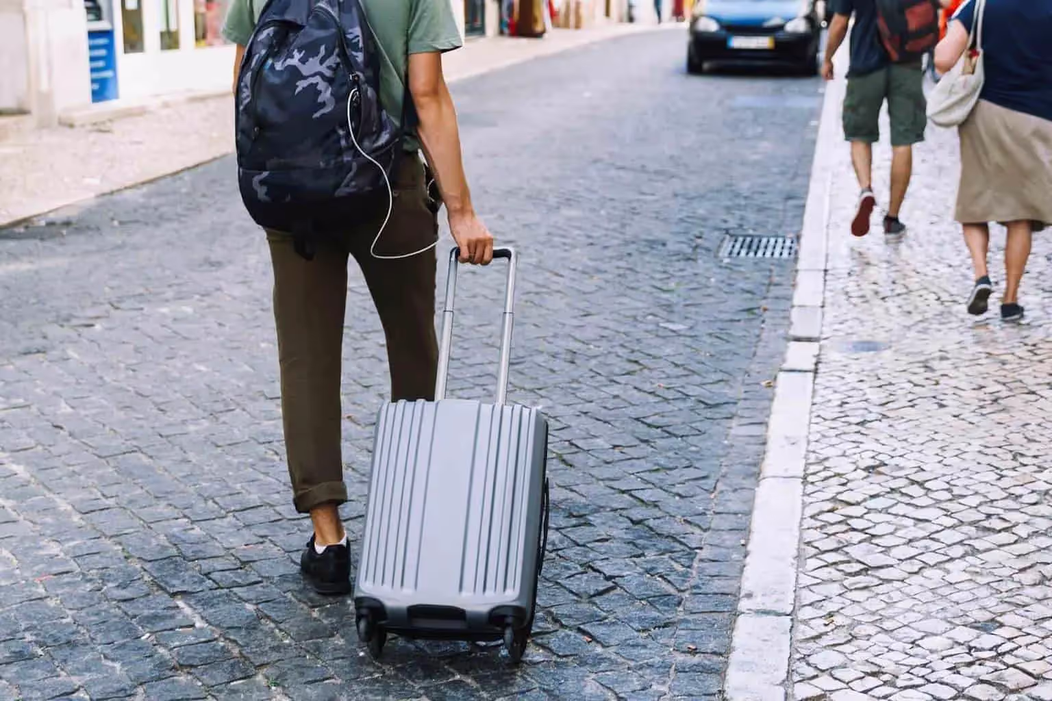 Person walking an cobblestone road with duffel bag