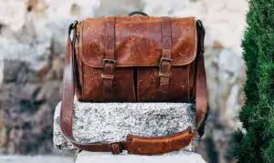 Leather travel bag propped up on rock outside