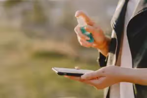 Person spraying sanitizer spray on smartphone