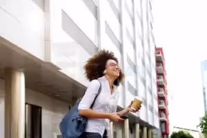 Portrait of smiling african female student walking with cellphone