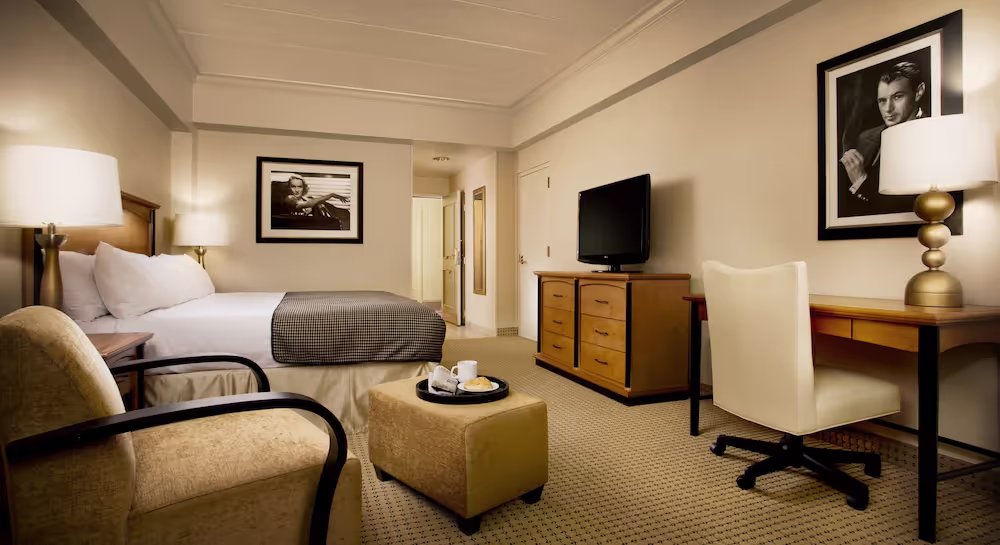 A hotel room with a bed and a televisionDescription automatically generated