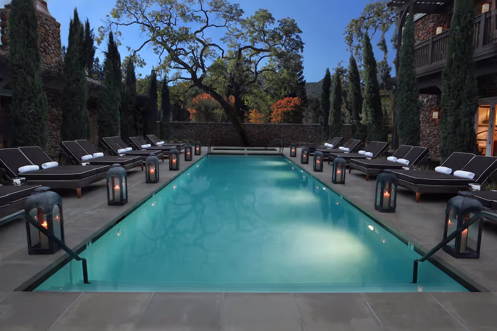 A pool with chairs and treesDescription automatically generated