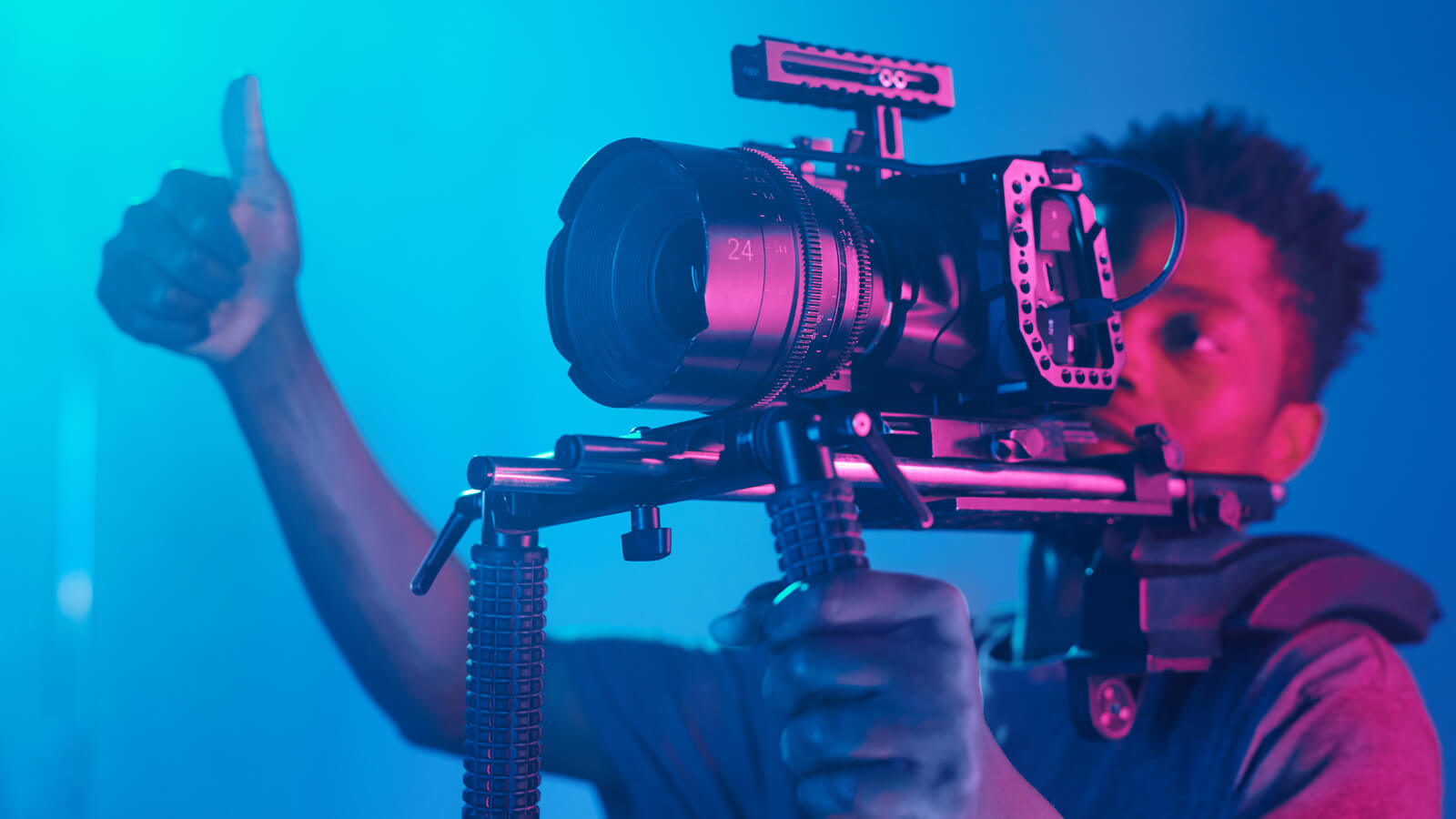 Man working behind a studio-quality camera giving a thumbs up