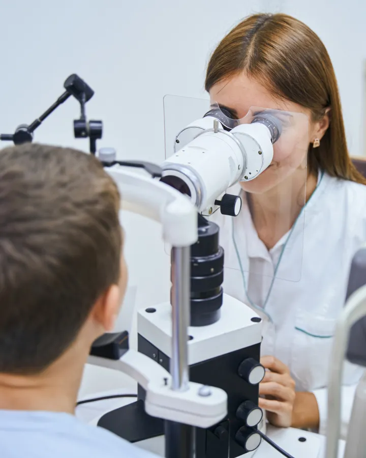 Optometrist conducting detailed children's eye examination using specialist pediatric equipment