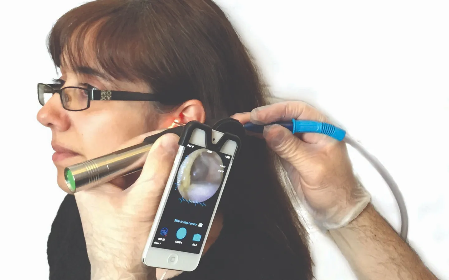 Professional audiologist performing digital ear examination using otoscope and smartphone technology during hearing assessment