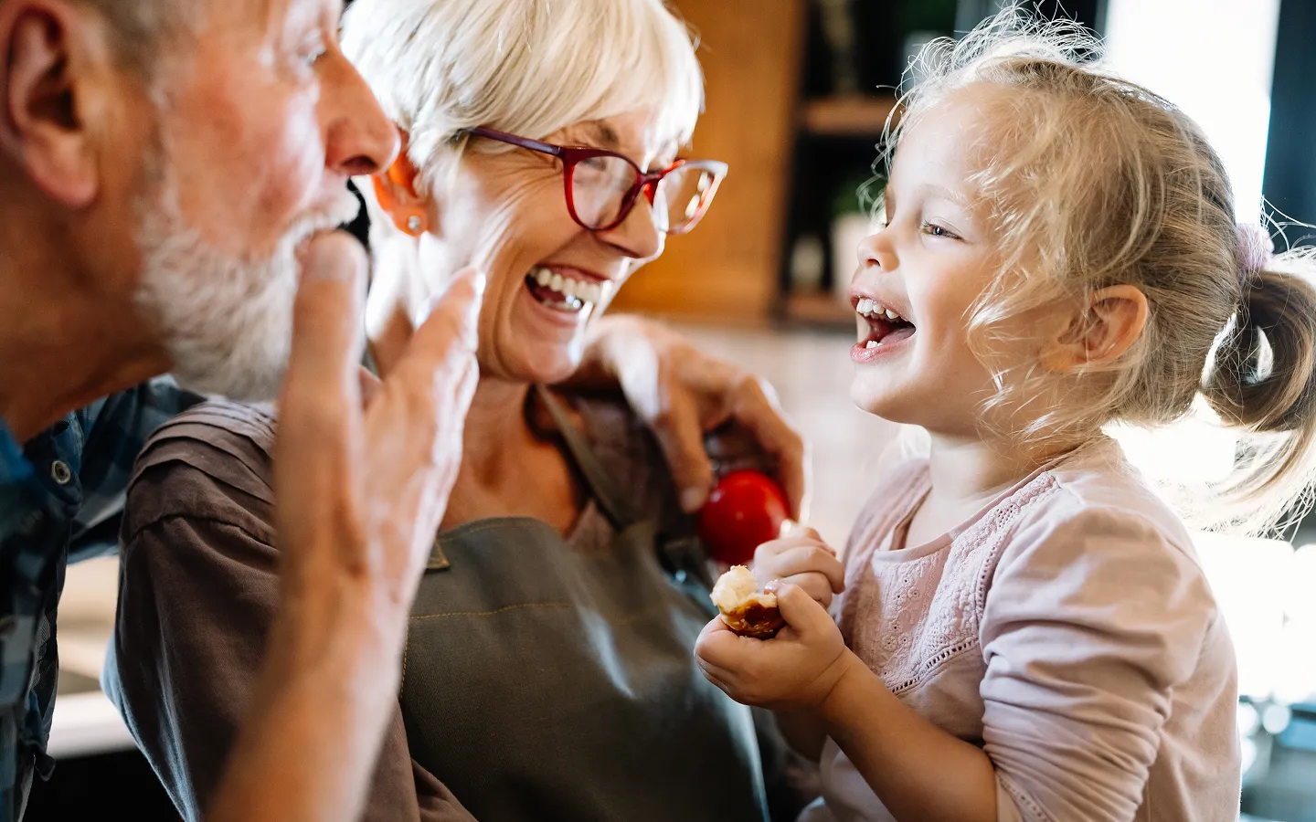 Grandparents with hearing aids enjoying clear communication and laughter with grandchild demonstrating hearing aid benefits
