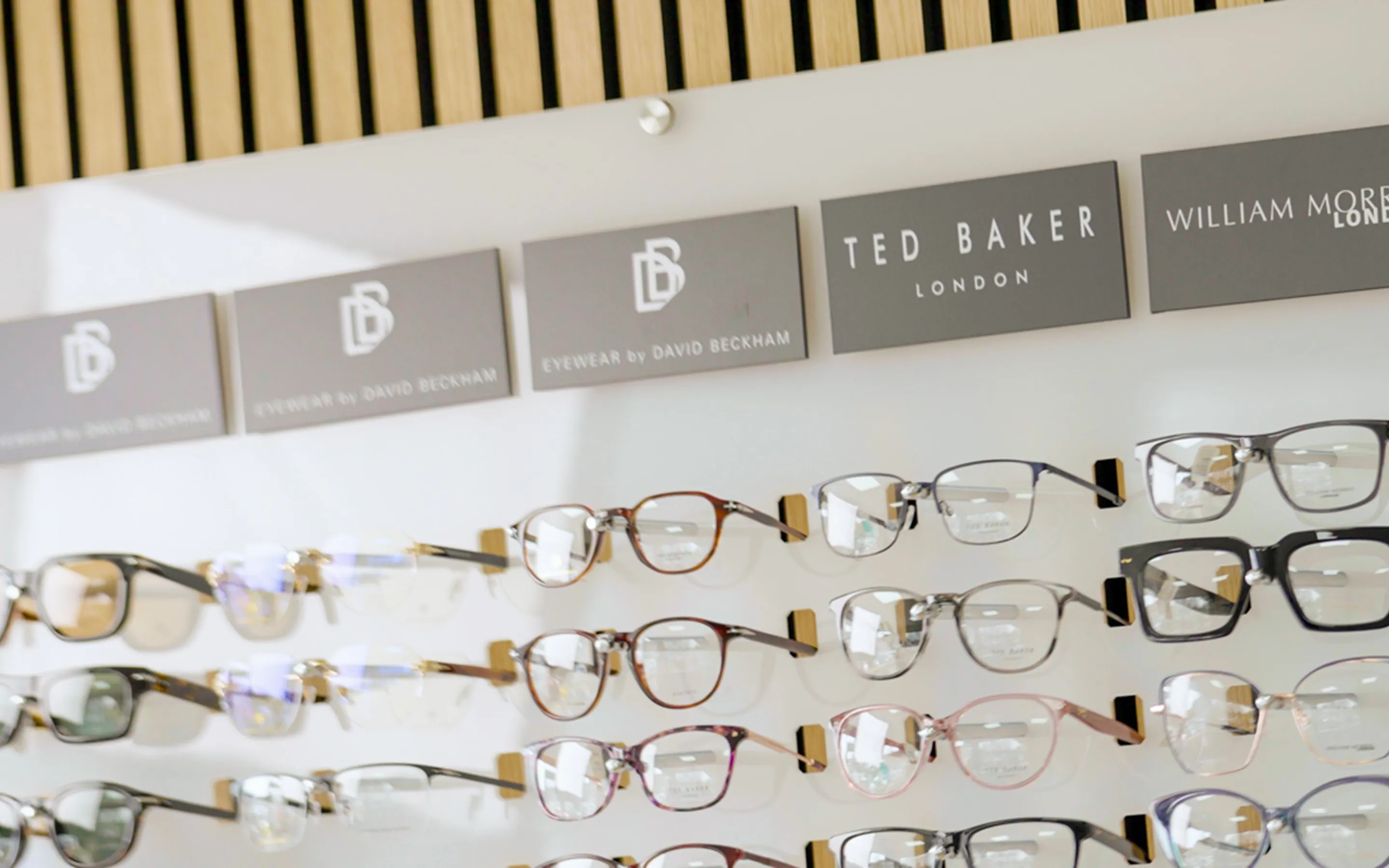 Display of various eyeglasses from brands including Eyewear by David Beckham, Ted Baker London, and William Morris London.