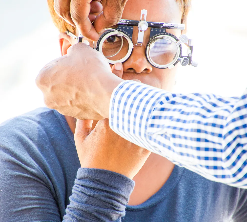 Woman receiving comprehensive eye examination with trial lens frame at opticians