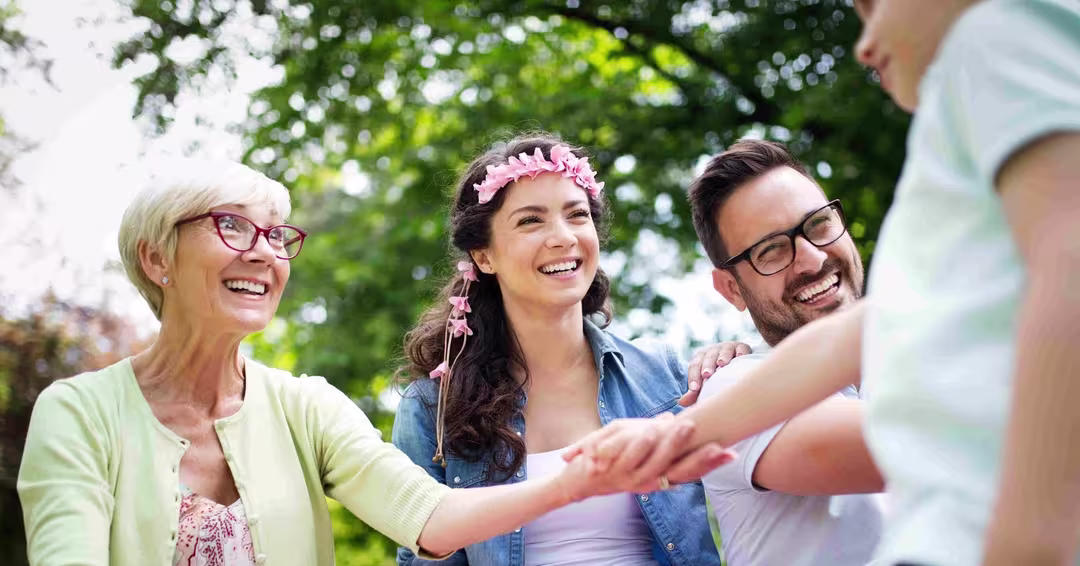 Smiling multi-generation family outdoors holding hands with blurred child in foreground.