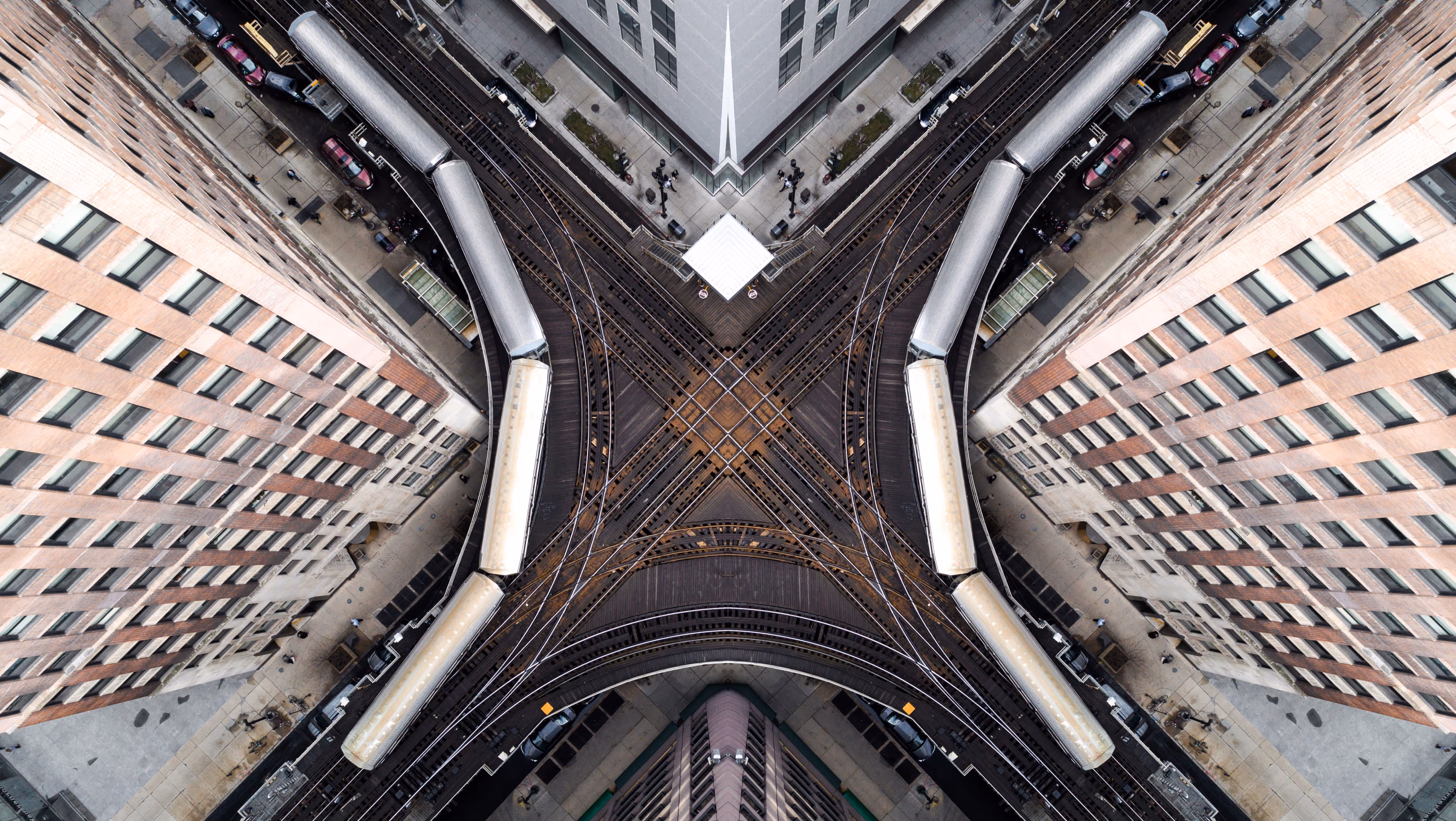Luchtfoto van een spoorwegkruising tussen hoge gebouwen met een stilstaande trein op het spoor.