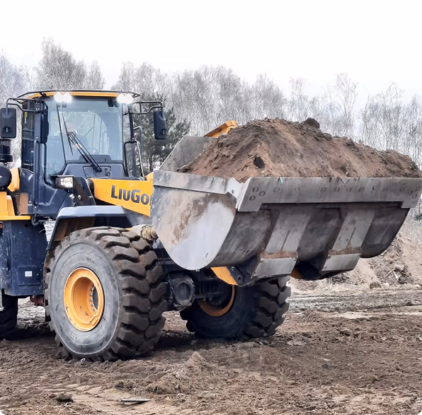 Gelber Radlader lädt eine große Schaufel mit Erde auf einer Baustelle.