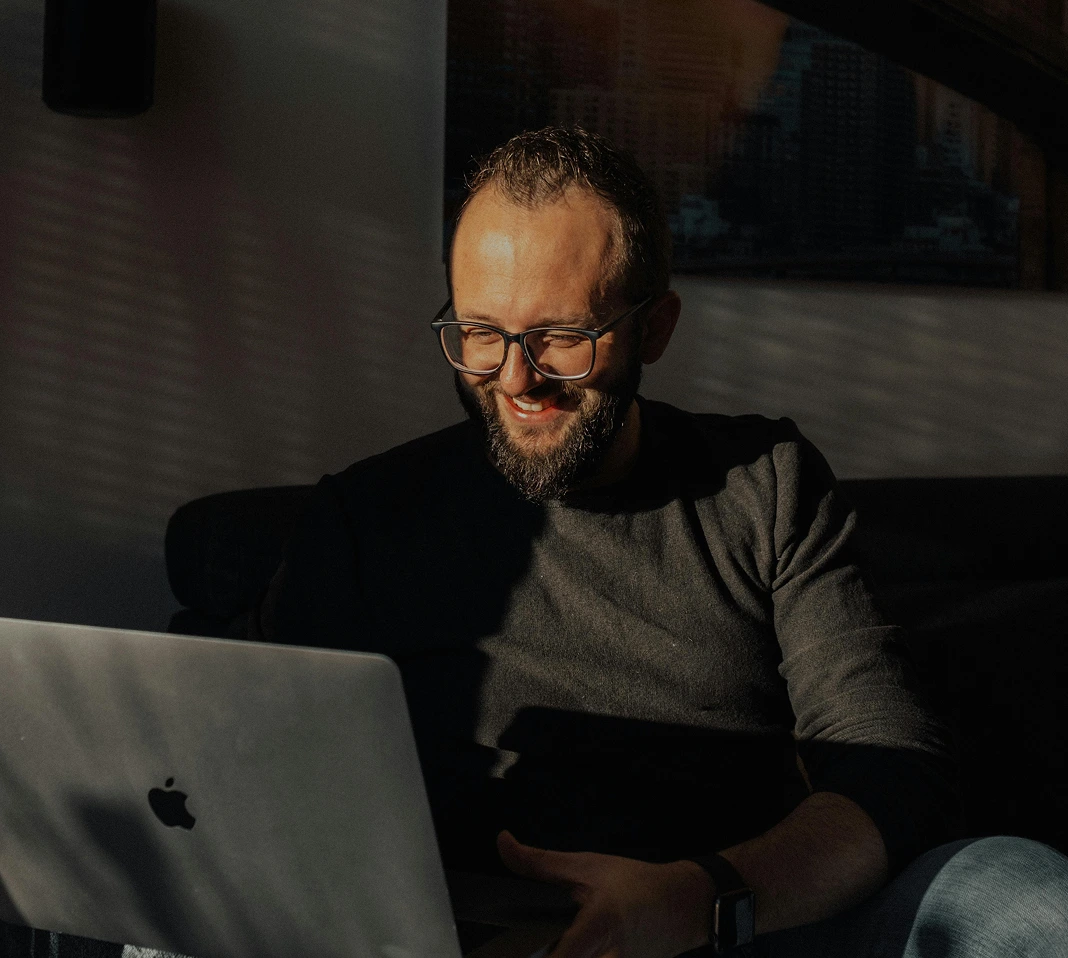 Homme souriant sur son canapé devant son ordinateur