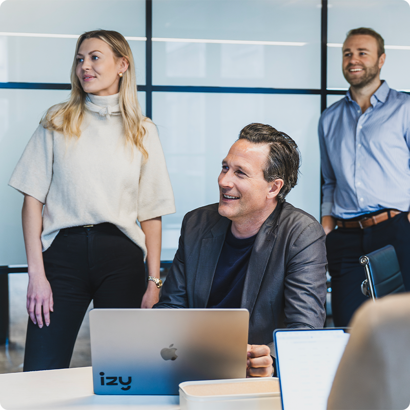 Ansatte i Izy i samtale rundt et møtebord med laptop.