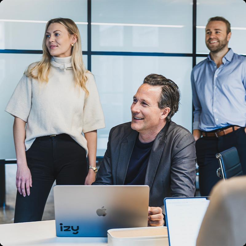 Ansatte i Izy i samtale rundt et møtebord med laptop.