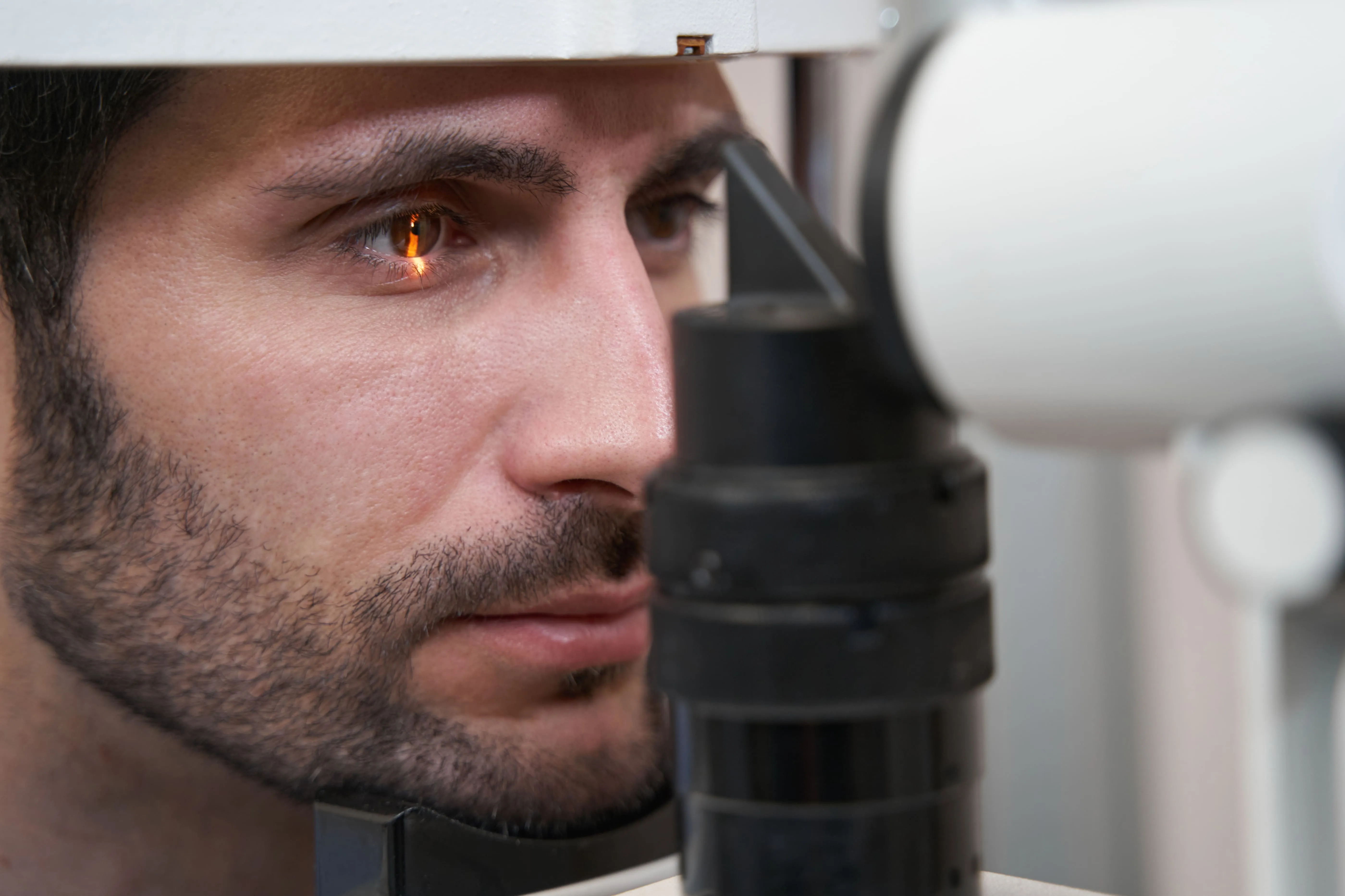 Close-up of a man undergoing an eye examination using a slit lamp device.